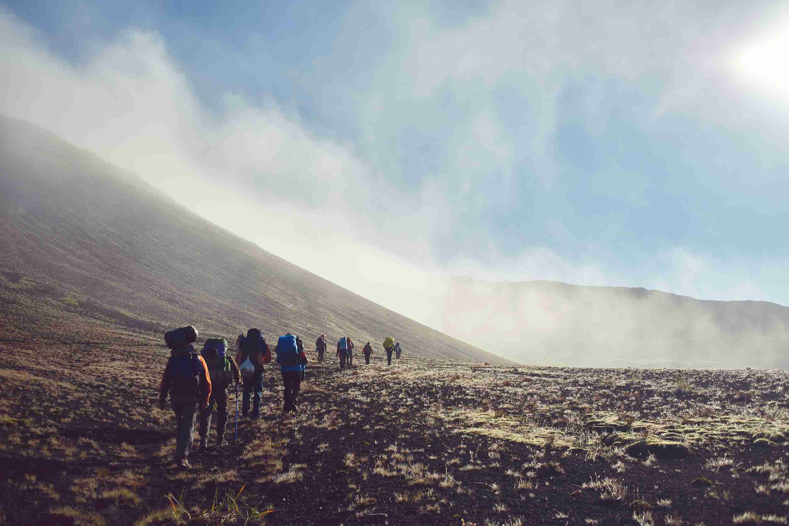 hikers on the trail in the in kilimanjaro. valley is in fog