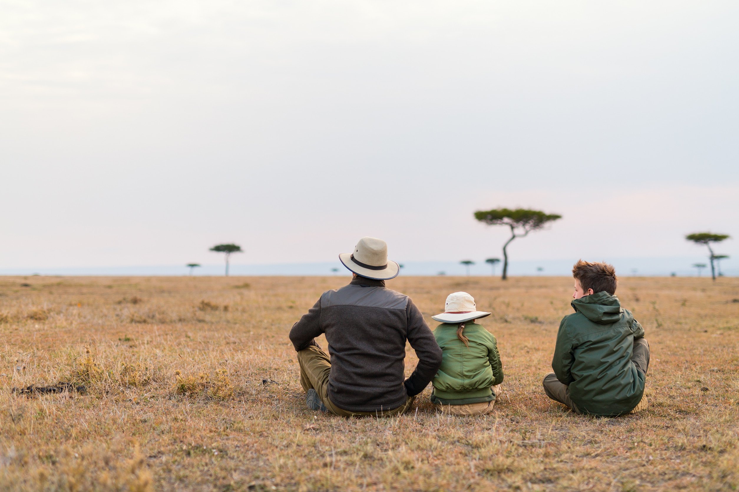 Family safari in Africa Family of father and kids on African safari vacation enjoying views over Masai Mara in Kenya