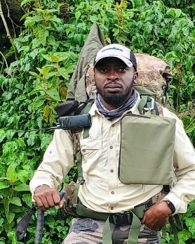 Innocent Mmari, trip leader, with a backpack and binoculars in the forest