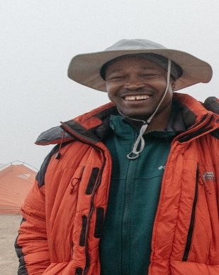 John Simon Maeda, mountain guide, smiling in a red jacket and hat