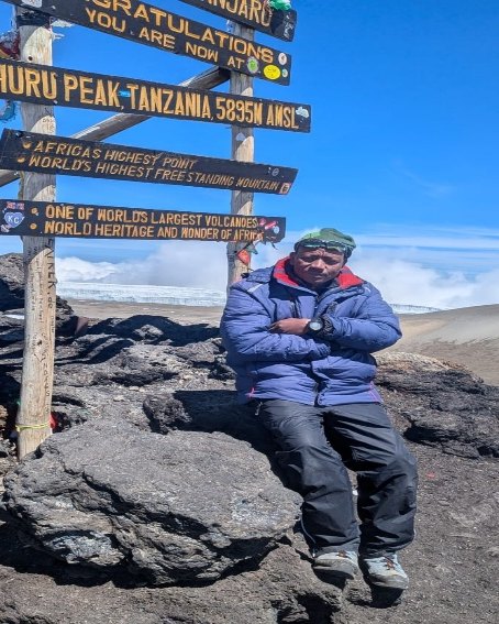 Samia Asindamu Tarimo, mountain guide, at the Uhuru Peak sign on Kilimanjaro